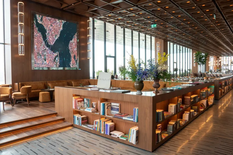 Lounge area of the Biz İstanbul, with sofas and chairs surrounded by low libraries and offering a view of Istanbul through the floor-to-ceiling glass windows