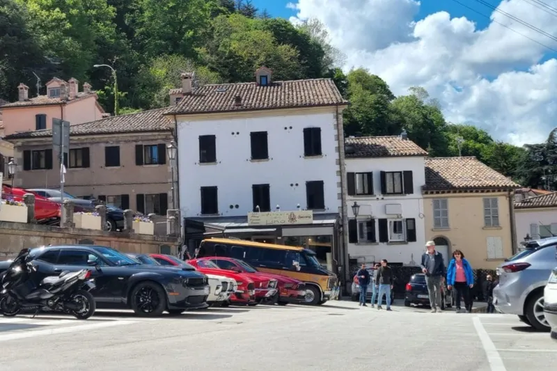 A view of Piazza Grande with cars parked and the Hostaria Da Lino Restaurant Pizzeria at the far end of the square
